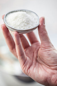 Cropped hand holding flour in bowl on table