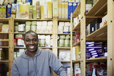 Portrait of smiling mid adult worker against racks in warehouse