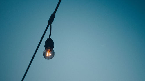 Low angle view of light bulb against clear blue sky