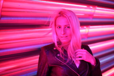 Portrait of smiling young woman standing in illuminated room