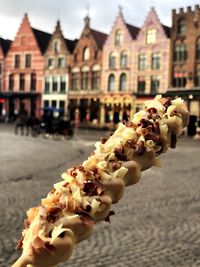 Close-up of hand holding ice cream on street against buildings