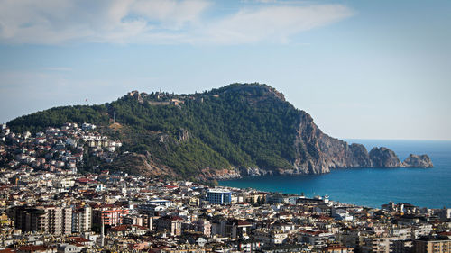 Aerial view of city by sea against sky