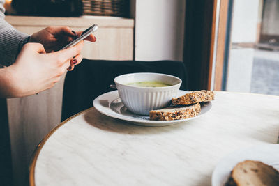 Cropped image of woman photographing food at home