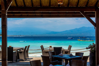 Empty outdoor restaurant at beach against sky