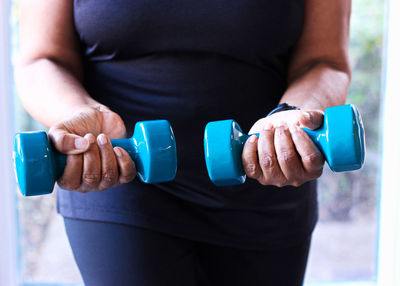 Close-up of senior black woman strength training with dumbbells for health and fitness.