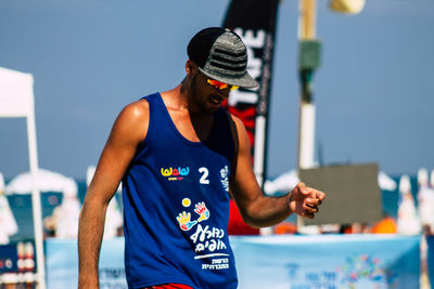 Midsection of man holding camera against clear blue sky