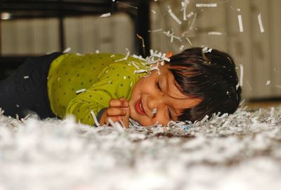 Side view of child lying down on papers