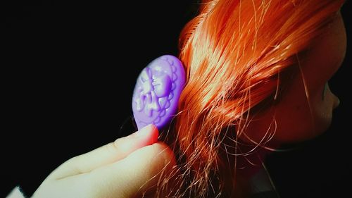 Close-up of a redhead doll over black background