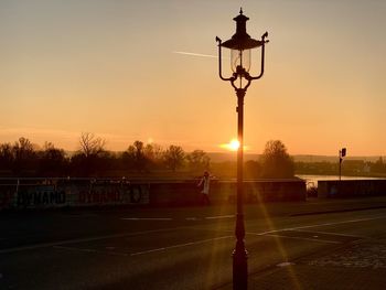 Street light on road against sky during sunset