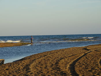 Man standing on beach against clear sky