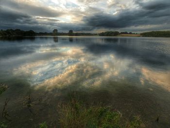 Scenic view of calm lake against cloudy sky