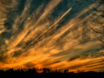 Low angle view of silhouette trees against dramatic sky