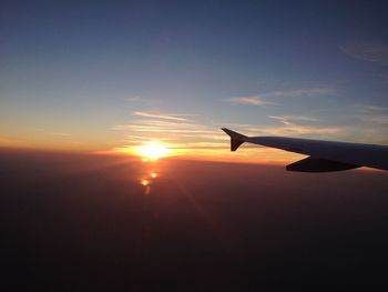 Airplane wing against sky during sunset