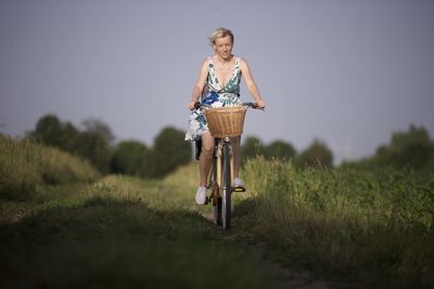 Portrait of young woman riding bicycle on field