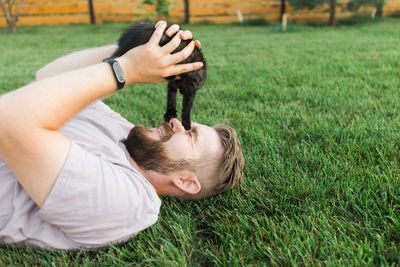 Man playing with cat lying on grass