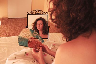 Portrait of woman sitting on bed at home