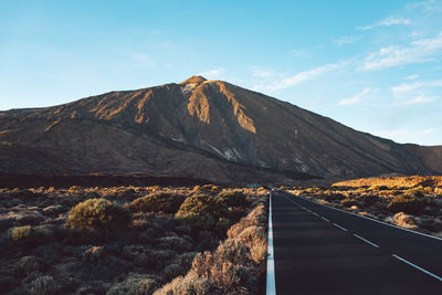 Road by mountain against sky