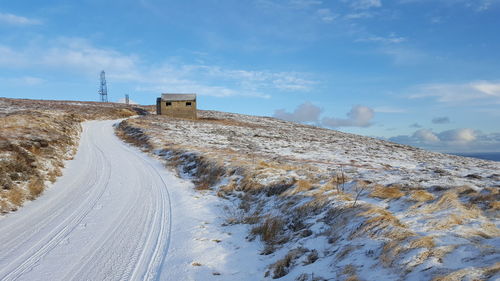 Road amidst snow covered land against sky