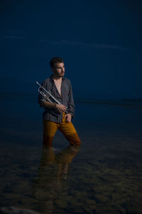 Young man looking away in sea against sky