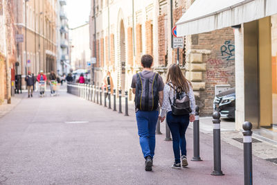 Rear view of people walking on street in city