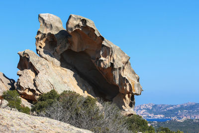 Low angle view of rock formation against clear blue sky