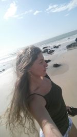Young woman on beach against sky