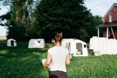 Rear view of siblings standing on grassy field in front of lawn