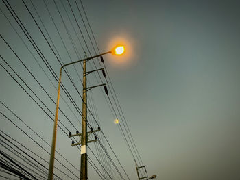 Low angle view of electricity pylon against sky during sunset