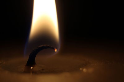 Close-up of lit candle against black background