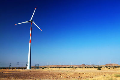 Wind turbine at desert against clear blue sky