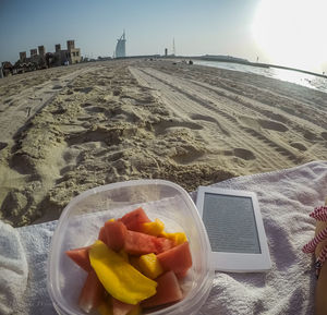 Close-up of fruits on sand against sky