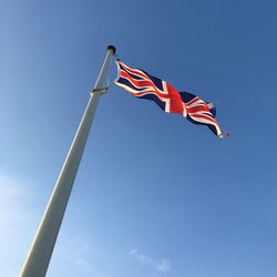 Low angle view of flag against blue sky