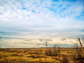 Electricity pylon on field against sky