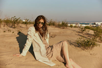 Young woman sitting on sand at beach