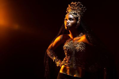 Woman in costume standing against black background