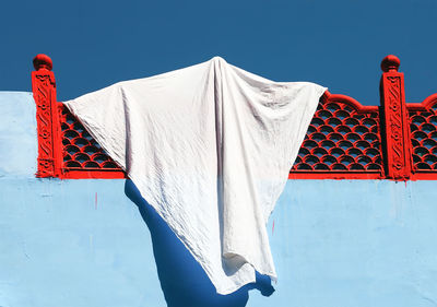 Low angle view of fabric hanging from red railing at building terrace