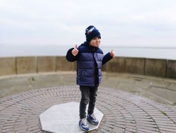 Full length of boy standing at observation point against sky