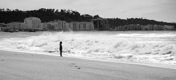 Rear view of man standing at beach against sky