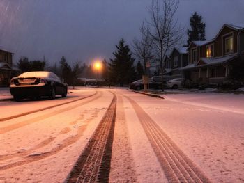 Cars on snow covered road against sky at night