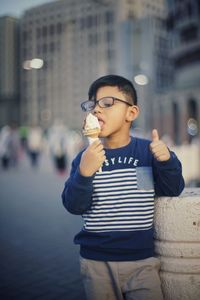 Close-up of happy boy holding umbrella in city