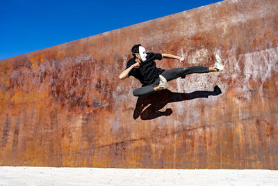 Low angle view of man jumping against wall