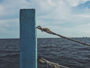 Wooden post in sea against sky