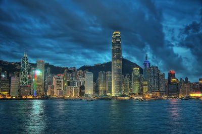 Illuminated buildings by city against sky at dusk