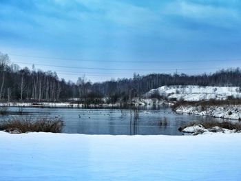 Trees on snow covered landscape against blue sky