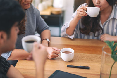 Midsection of couple holding coffee while sitting at table