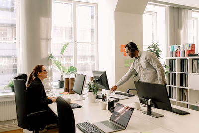 Smiling business colleagues talking at desk in office