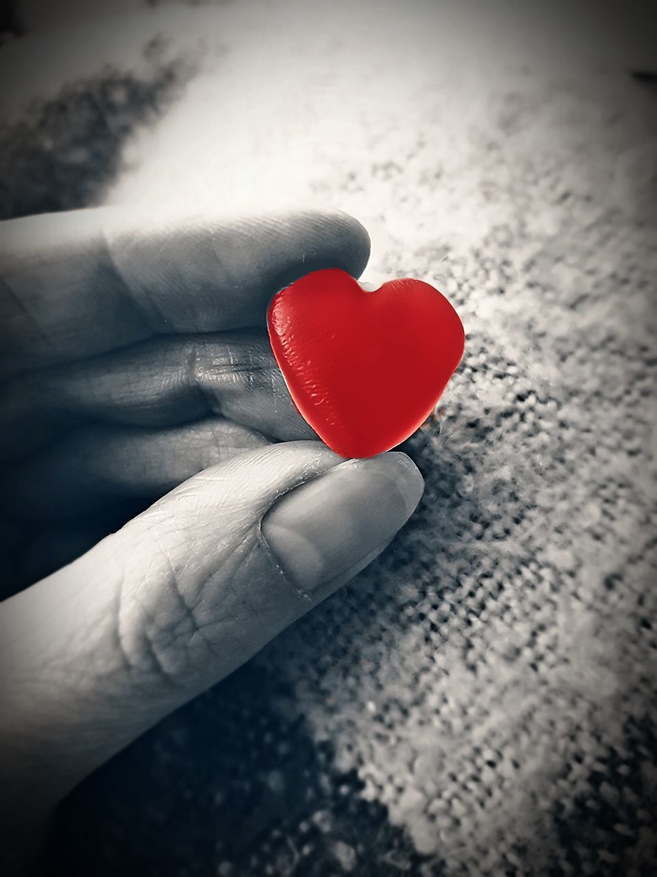 CLOSE-UP OF HAND HOLDING RED HEART SHAPE ON LEAF