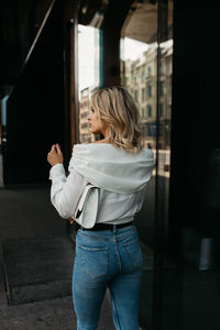 Fashionable woman standing against window in city