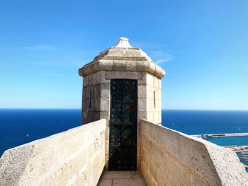 Built structure by sea against blue sky