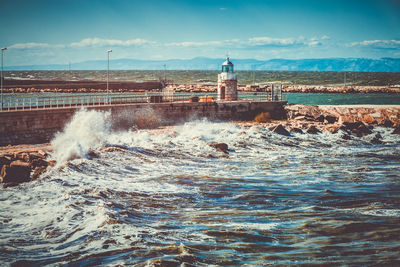 Lighthouse by sea against sky